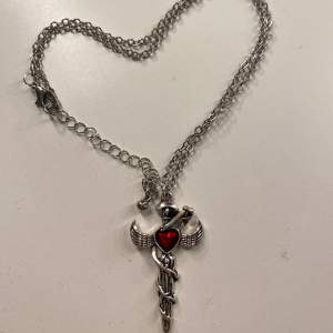 Jättefint halsband med ett svärd, vingar och ett rött hjärta ❤️🗡️🪽köptes för ca 100kr+ men säljer ganska billigt. Köpte på en marknad, därför vet jag inget märke 