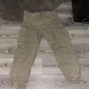 Cargo byxor - Sköna ganska tunna cargo byxor, bra under sommaren, väldigt bra skick. Finns dragkedja strax över knäna för att ta bort undre byxben så man kan ha byxorna som skjorts, säljer för ja inte använder de längre, legat i en låda länge, drf de e skrynliga