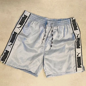 Vintage Puma shorts stl M - Klassiska Puma stripe shorts i ovanlig ljusblå färg, väl använda men hela. Något noppiga på baksidan. 