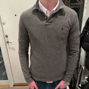 Ralph Lauren långärmad piké - Långärmad grå piké från Polo Ralph Lauren! Snygg tröja i storlek S men sitter som M! Modellen på bilden är 183 cm lång!  Den är i jättebra skick och sparsamt använd! Nypris över 1500kr mitt pris 350! Vid snabb och smidig affär kan pris diskuteras! 