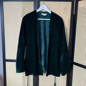 Grön kavaj i sammet H&M - Fint använt skick - otrolig grön färg 💚 Tvinnat skärp som kan tas bort  Enda skavanken är att en av tofsarna på skärpet är borta (se bild) 