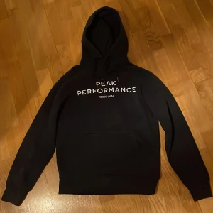 Peak performance hoodie - Mörkblå hoodie i storlek M. Det är i rätt så bra skick trots använd flertal gånger. Skriv om frågor eller fler bilder!