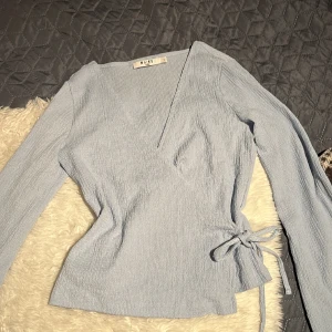 Blå omlott top - Blå omlott topp med utsvängda armar  Storlek S från NA-KD Säljes för 30kr+fraktpris