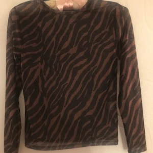 Tunn överdel  - Tunn överdel med långa ärmar. Nästan aldrig använd. I storleken 146/152 från märket Skill. Fint mönster i svart och brunt. Är av polyester och elastan. 