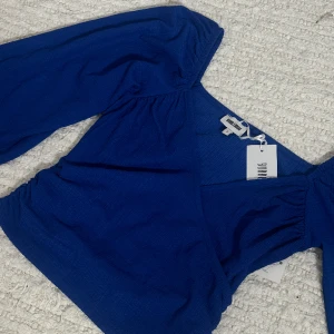 BLÅ TOPP - Denna blåa topp säljs, oanvänd, med prislapp. Lite fina detaljer, ballongärmar 💙🦋