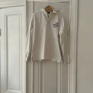 Rugby från polo Ralph Lauren Färg vit, med snygga detaljer.  Fint vintage skick, med det menas att de finns absolut missfärgningar och mindre skavanker efter att antal år på nacken!