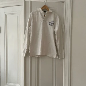 Ralph Lauren Rugby  - Rugby från polo Ralph Lauren Färg vit, med snygga detaljer.  Fint vintage skick, med det menas att de finns absolut missfärgningar och mindre skavanker efter att antal år på nacken!