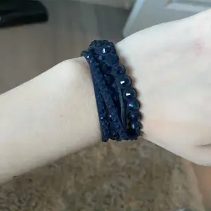 Ett marinblått armband som har även fina detaljer på sig 