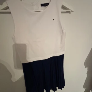 Tommy Hilfiger Klänning - Super söt tommy hilfiger klänning i bra skick, Vit topp och marinblått tunt refflat tyg nedtill. Perfekt till sommaren🤩 (osäker om storleken, det står inte, passar mig som normalt är en S)