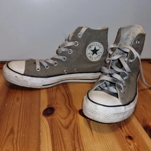 Converse All Star "Chuck Taylor" - Grå Converse i mycket bra skick. Inte nötta, varken sula eller tyg, men någon smutsfläck på det vita. Skosnörena kan man ju byta om man tycker de är slitna. Storlek 5 (ca 37,5). Säljer för att de tyvärr blivit för små.