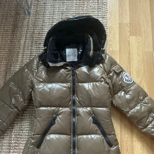 Moncler jacka - Moncler jacka i jättefint skick! Köpt på Vestiaire collective med äkthetkoll. Inga fläckar eller hål. Bara lite lösa trådar vid cartoonen. Storlek 0 och passar mig som har xs/s. Olive/brun färg❤️säljer för jag inte använder den!
