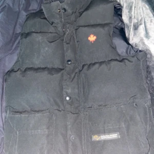 canda goose väst - har en canda goose väst jag tänkte sälja då den inte passar längre, den är en äldre modell därför de är ett löv och inte jordglob. Ända defekter är att 2knappar saknas men kan fixas om man har extra knappar. skick 9/10 om man bortser knapparna:)S/XXS