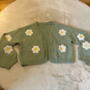 Grön stickad kofta med vita blommor - En supersöt grön kofta med vita blommor