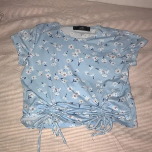 Blå top med vita blommor - Köptes för 280 kr och är I bra kvalitet.