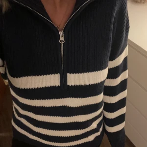 Stickad Zip-tröja - En marinblå/vit randig stickad tröja med dragkedja. Tröjan är använd fåtal gånger.