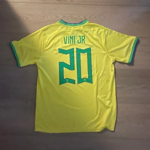 Brasilien Tröja med Vini Jr#20 - Säljer denna splitternya Brasilien hemmaställ med Vini Jr#20 på ryggen, som säljes eftersom jag fick fel storlek och inte kan lämna tillbaka den. Storleken är XL, men passar även L