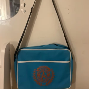 Blå väska - Blå Väska med stor ficka på framsidan och två mindre på insidan Rektangulär i formen Lätt att packa saker i Säljs för att jag inte använder den