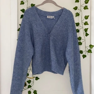 Stickad kofta - En fin blå stickad kofta från Weekday. Koftan är i fint skick och har en väldigt lös passform.