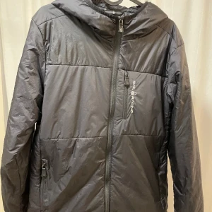 Sail racing jacka  - Sail racing jacka i svart säljes för att den blivit liten. Strl 170.  Helt ok skick, litet hål till vänster på ryggen intill mudden.