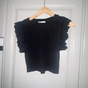 ZARA volang topp🖤🪩 - ZARA topp i storlek M🪩 den har volanger på sidorna av ärmarna och är gullig och enkel att styla ( snyggt med t.ex blå bootcut jeans)🪩🙏🏻 den är väl använd med ändå i fint skick.