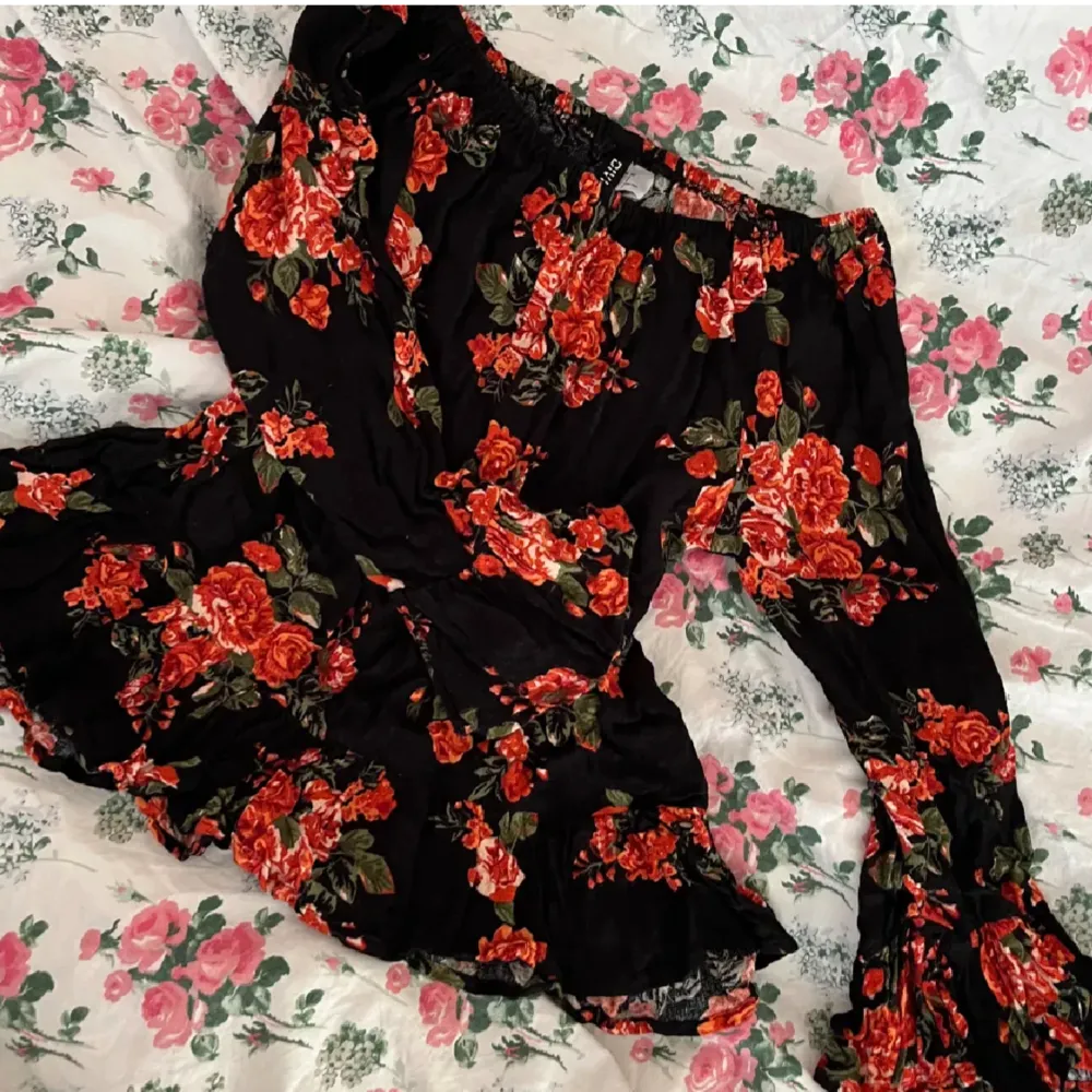 En svart off-shoulder blus med röda blommor med lätt utsvängda armar samt volang vid ärnslut och nedtill från H&M i strl XS!💓. Blusar.