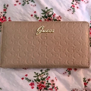 Plånbok - Beige plånbok ifrån Guess som ryms mycket i, lapparna är kvar och den är helt oanvänd. Kommer i en fin liten box dessutom. Köpt tidigare för 440 på rea 🤍