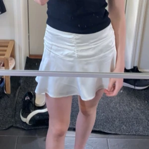 Vit minikjol - Säljer min vita minikjol från bershka! Den har en dragkedja på sidan och små volanger längst ner. Jag säljer den då den blivit lite för liten, men har knappt använts och är i mycket bra skick. Skriv privat för fler bilder🩵