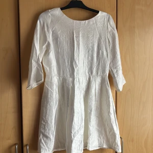 Vit klänning i festlig lättskimrig tyg - Vit klänning i vit lätt skimmrig tyg perfekt från studenten, konfirmation till bröllopet. Helt ny aldrig använt. Dragkedja på baksidan
