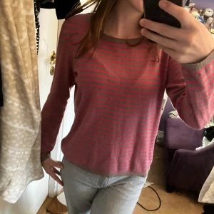 Tröja från H&M - Jätte söt grå och rosa randig tröja från H&M. Inte riktigt i nyskick men inga defekter förutom en liten svart fläck vid armen. Har dock inte försökt få bort det så går säkert bara att tvätta. Storlek S (köparen står för frakten)