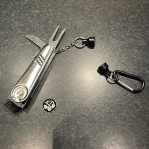 Golf verktyg greenlagare - Säljer ett multifunktionellt golfverktyg framtaget av mitt UF-företag golf in one. Verktyget har en utfällbar greenlagare, borste, rengöringskniv, skruv för dobbarna och en markeringskkapp. Fäst i en karbinhake med magnet som enkelt tas av från bagen