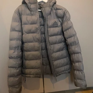 Adidas dunjacka - En varm och skön vinterjacka med ltäcken på användning vid armslutet på båda ärmarna, syns inte på långt hål. Man kan dra åt den i midjan.