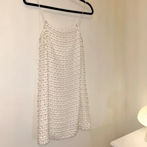 Underbar kort klänning med pärlor  - Mini dress i rak modell från HM täckt i pärlor! Storlek XS. Kort klänning med ganska liten byst. Justerbara smala axelband. Aldrig använd men på enstaka ställe finns någon tråd där en pärla lossnat.