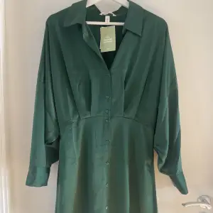 HELT NY, OANVÄND! Grön långärmad satin klänning i skjortmodell. Super fint material och färg, men lite för liten för mig. Känns mer som en small. Lappen sitter kvar och är endast testad💚