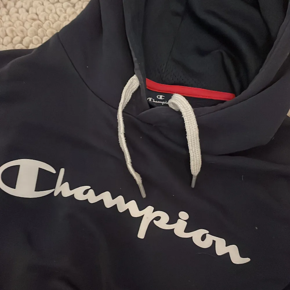 Mörkblå champion hoodie med text på bröstet. Hoodies.