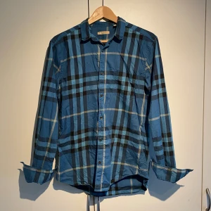 Burberry Skjorta  - Hej, säljer en blå Burberry skjorta i det klassiska mönstret. Bra skick utan defekter. Storlek M och true to size. Sällan man ser denna färgen på marknaden. Passar lika bra i vardagen som på fest. Pris kan diskuteras. Hör av dig vid intresse. 