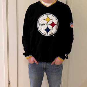 En svart Steelers sweatshirt i storlek XL. Kvaliten är bra och det finns en NFL logga inuti tröjan.