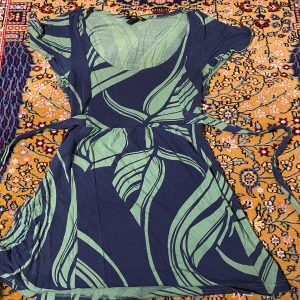 Mönstrad blus  - Mönstrad blus i grönt och blått med band så man kan göra den så tajt som man önskar. Sparsamt använd, så i fint skick.