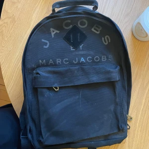 Marc by Marc Jacobs ryggsäck - Svart ryggsäck från Marc by Marc Jacobs i tyg med mockadetaljer. Har aldrig använt denna, så i nyskick. Rycksäcken har legat nedpackad, därav lite dammig.