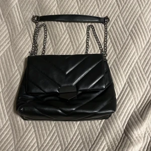 Svart handväska  - Liten men rymmer jättemycket har två fak och är i bästa kvalitet bara använd 1 gång och väldigt fin nu till sommaren pris går att diskuteras 