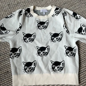 Vit tröja med kattmönster från & Other Stories - Säljer en superfin vit tröja från & Other Stories med ett gulligt kattmönster i svart. Tröjan är i storlek S och är perfekt för både vardag och mysiga hemmakvällar. Den är gjord av mjukt material och har en normal passform. 