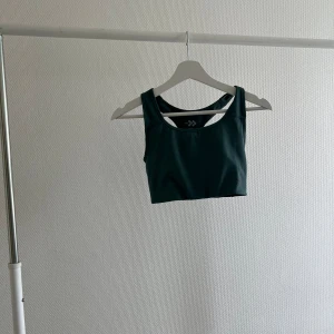 Grön linnetopp - En grön gymtopp med breda axelband och en enkel design. Toppen är ärmlös och har en rund halsringning.