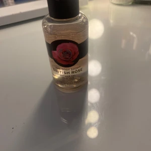 British Rose Shower Gel från The Body Shop - Säljer en British Rose Shower Gel från The Body Shop. Den kommer i en genomskinlig flaska med svart lock och en etikett med en rosa ros på. Duschgelen har en härlig doft av rosor och är perfekt för att fräscha upp sig med i duschen. Flaskan är liten och smidig att ta med sig, perfekt för resor eller gymväskan. Köp direkt eller ge prisförslag 🌹