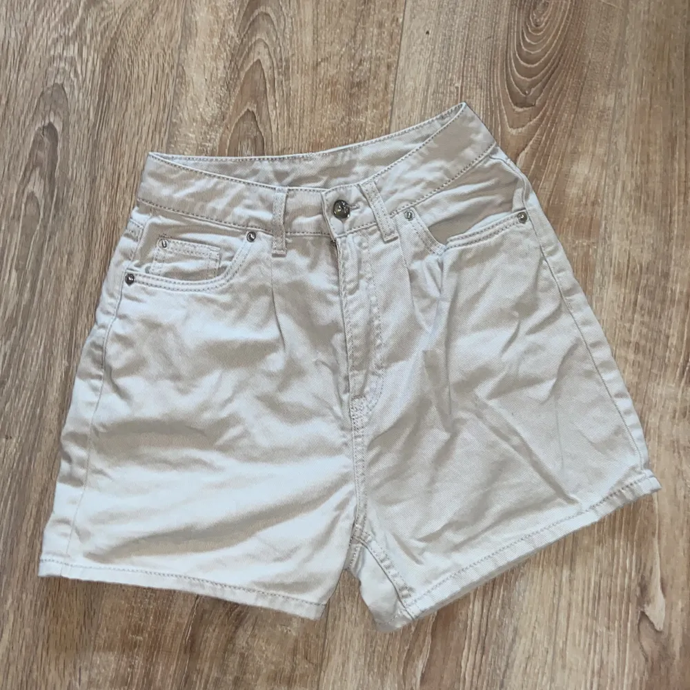 Säljer ett par snygga beige shorts från H&M i storlek 34. De är gjorda av bomull och har en normal passform. Shortsen har fyra fickor och knappar framtill. Perfekta för sommaren!. Shorts.