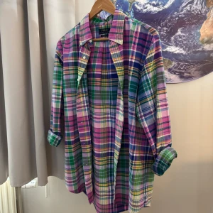 Flerfärgad rutig skjorta från Polo Ralph Lauren - Säljer en snygg och färgglad rutig skjorta från Polo Ralph Lauren. Skjortan har en mix av färger som rosa, grön, blå och gul. Den är långärmad och har knappar hela vägen ner. Perfekt för både vardag och fest!