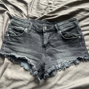Svarta jeansshorts med fransar - Säljer ett par snygga svarta jeansshorts med fransar i nederkant. De är i bra skick och har en låg midja. Perfekta för sommaren! säljer då de tyvärr blivit för små❤️