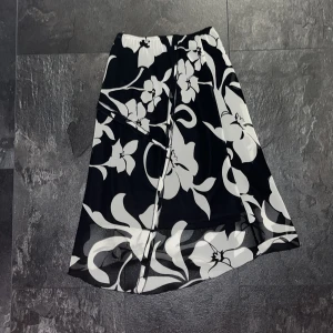Blommig kjol - En classy svart och vit blommig kjol, medellång till knäna för mig som är 170cm. Töjbar i midjan.