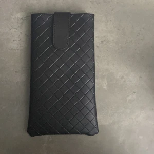 Svart quiltad plånbok från Bottega Veneta - Säljer en elegant svart quiltad plånbok från Bottega Veneta. Plånboken har ett stilrent rutmönster och en praktisk stängning med en flik. Perfekt för att hålla dina kort och kontanter säkra. Passar både till vardags och fest!