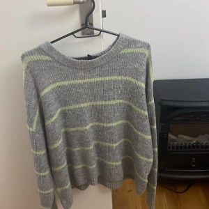 Grå och gulrandig stickad tröja - Säljer en mysig grå stickad tröja med gula ränder. Tröjan har en normal passform och långa ärmar. Perfekt för höst och vinter! 🧡