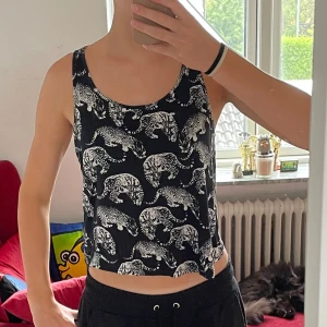 Svart och vit leopardmönstrad linnetopp från Gina Tricot - Säljer en snygg svart och vit leopardmönstrad topp från Gina Tricot. Toppen är ärmlös och croppad, perfekt för sommaren. Den är tillverkad av 100% ekologisk bomull vilket gör den både bekväm och miljövänlig. Den är ganska lös och passar därför xs-m. 