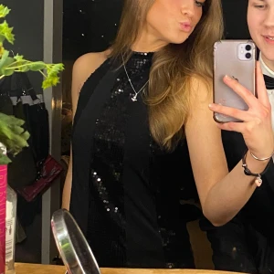 Svart paljettklänning - Säljer en snygg svart haltertopp med paljetter. Framhäver figuren. Perfekt för fest och nyår! köpte den secondhand för något år sedan, några paljetter sitter lite löst men annars i toppen skick